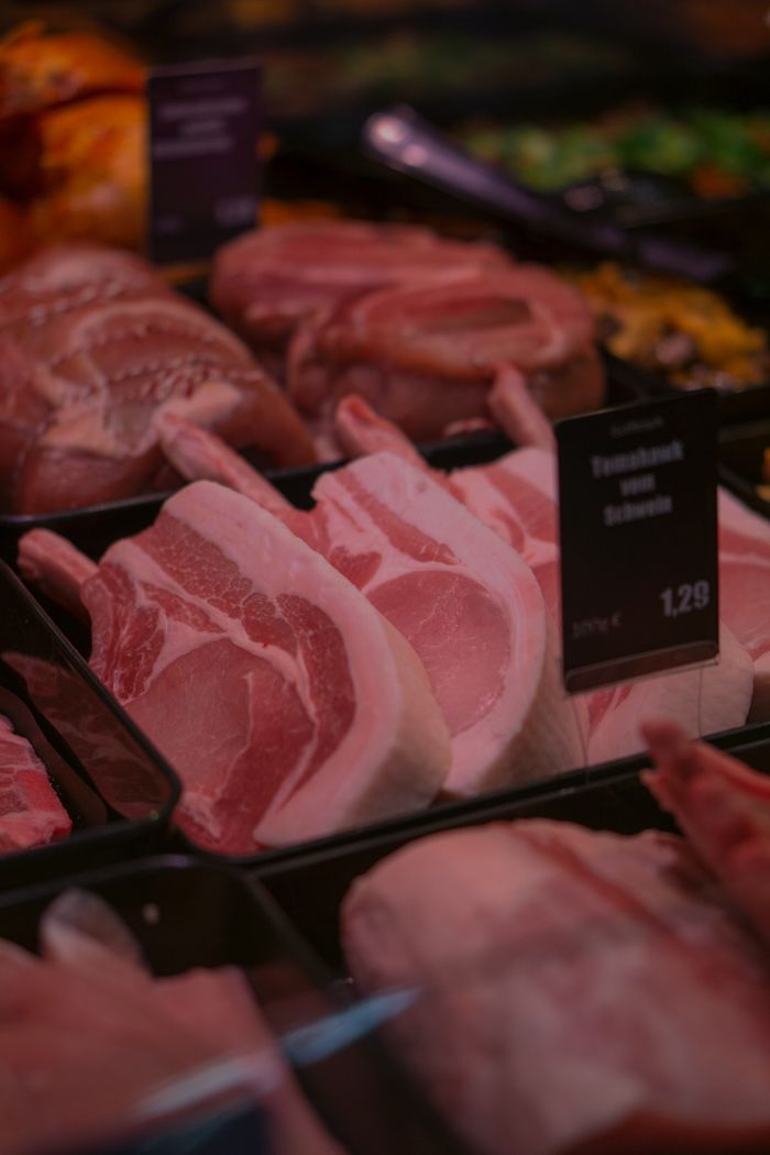 programs-01 Fresh raw pork chops on display in a butcher shop, ready for sale.