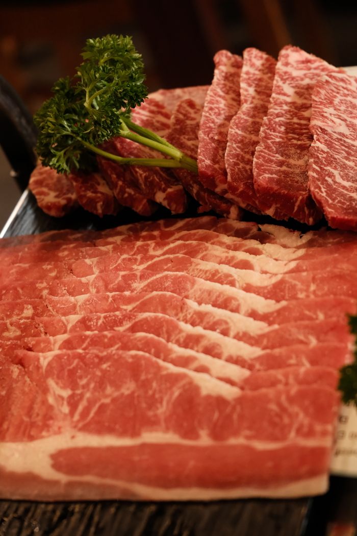 Close-up of marbled beef slices on a tray with parsley, perfect for cooking enthusiasts.