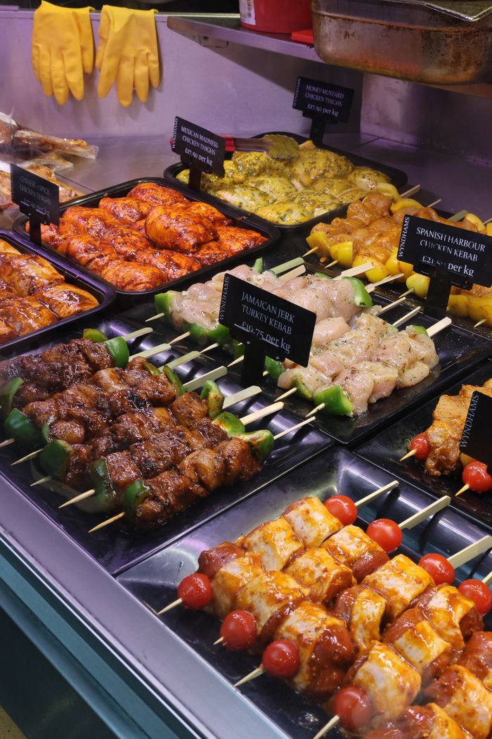 Close-up of various marinated meat skewers in a market display. Ideal for food-themed stock images.